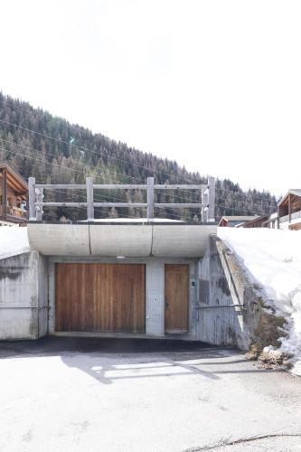 a building with two garage doors and snow on the ground at Quiet corner with charm in Obergesteln in Obergesteln