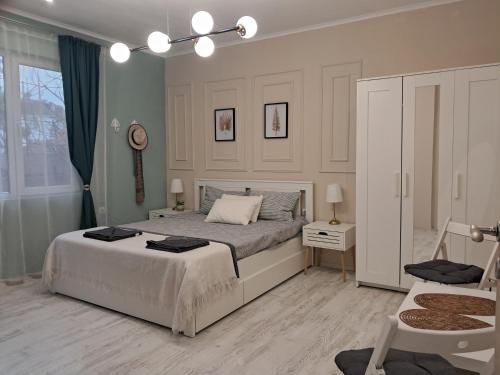 a white bedroom with a bed and a chair at Varna Moreto in Varna City