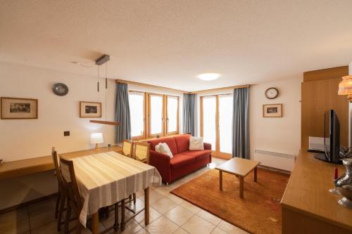 a living room with a red couch and a table at Quiet corner with charm in Obergesteln in Obergesteln