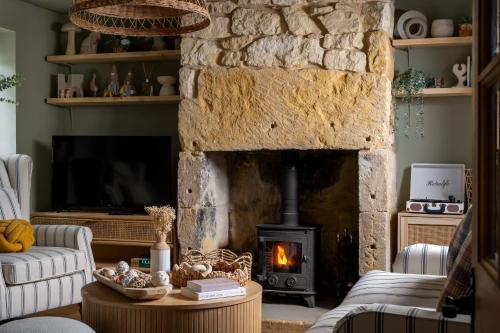 a living room with a stone fireplace and a couch at Broadway Scandi Chic Authentic Cottage in Broadway