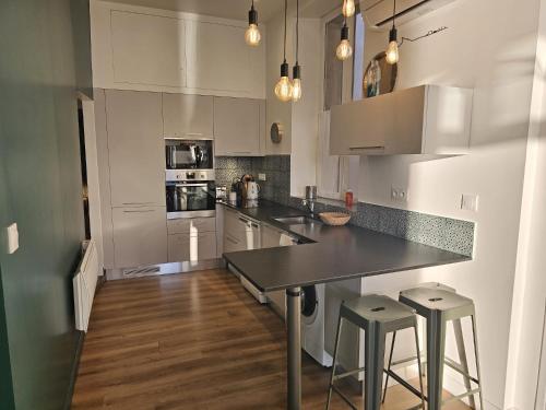 une cuisine avec des armoires blanches et un comptoir noir dans l'établissement Magnifique 3 chambres, vue sur le port, clim., à La Ciotat