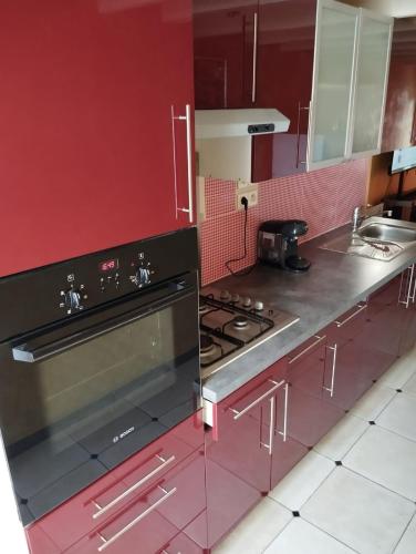 La cuisine est équipée de placards rouges et d'un four avec plaques de cuisson. dans l'établissement Maison 2 faces Argeles Centre Ville, à Argelès-sur-Mer