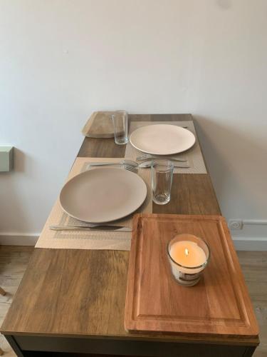 - une table avec deux assiettes et une bougie dans l'établissement Appartement La case a vent, à Fort-Mahon-Plage
