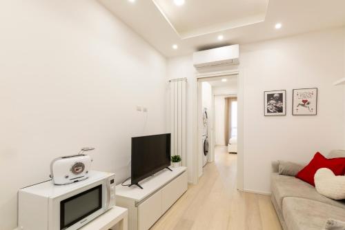 een witte woonkamer met een tv en een bank bij Campus Bligny - Bocconi District in Milaan