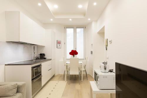 een keuken met witte kasten en een tafel met stoelen bij Campus Bligny - Bocconi District in Milaan