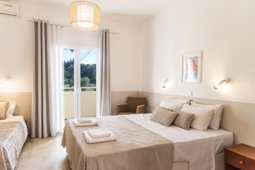 a white bedroom with a bed with towels on it at BOHOTEL Eleonas Anex Apartments in Kavos