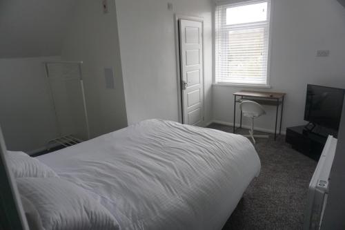 a bedroom with a bed and a desk and a television at Horsforth Rooms by LBA in Horsforth
