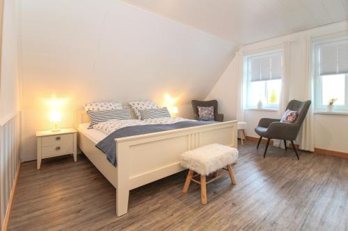 a bedroom with a bed with two chairs and two windows at Brise8 - Greetsiel in Krummhörn