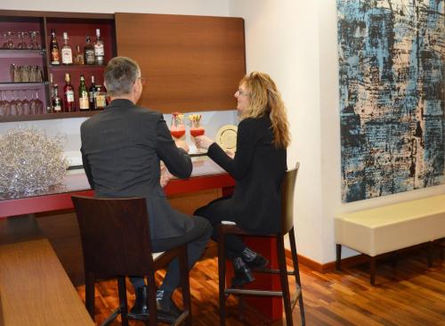 a man and a woman sitting at a bar at Astoria Hotel Italia in Udine