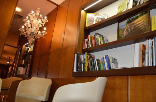 a dining room with white chairs and bookshelves at Astoria Hotel Italia in Udine