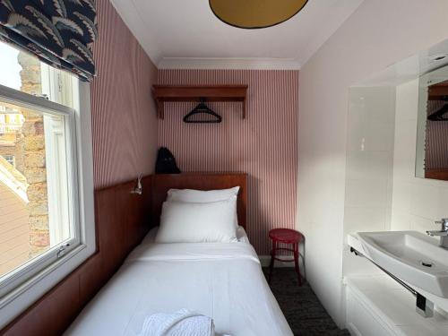 une petite chambre avec un lit et un lavabo dans l'établissement St. David's Hotels Paddington, à Londres