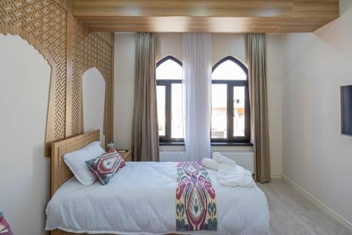 a bedroom with a bed and two windows at Volidam Hotel in Samarkand