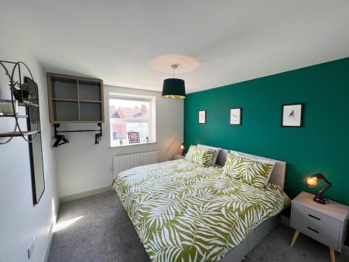 a bedroom with a bed and a green wall at Modern Two Bed House With EV Off Road Parking in Henwick
