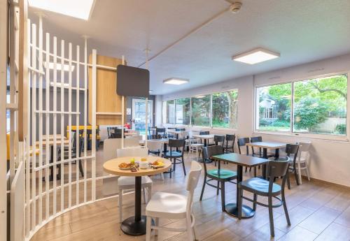 a restaurant with tables and chairs and windows at B&B HOTEL Lyon Centre Monplaisir in Lyon