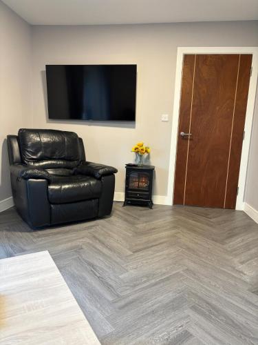 a black leather chair in a living room with a flat screen tv at The Drey in Poole