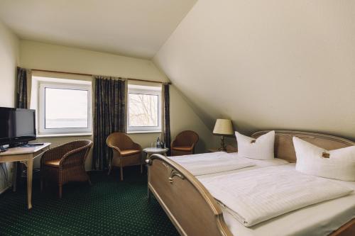 a bedroom with a bed and a desk and a television at Seehotel Heidehof in Klein Nemerow