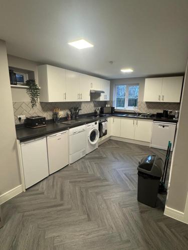 a kitchen with white cabinets and a washer and dryer at The Drey in Poole