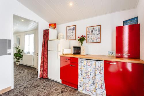 Il comprend une cuisine équipée de placards rouges et d'un réfrigérateur rouge. dans l'établissement Maisonnette centre ville, à La Rochelle