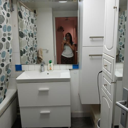 une femme prenant une photo dans un miroir de salle de bains dans l'établissement proche Paris chambre hôte, au Kremlin-Bicêtre