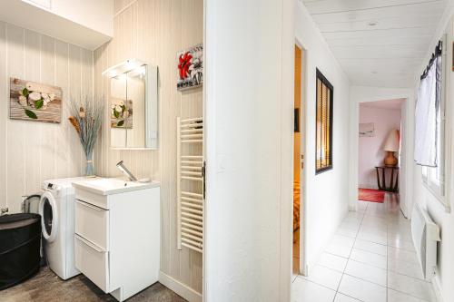 La salle de bains blanche est pourvue d'un lave-linge et d'un sèche-linge. dans l'établissement Maisonnette centre ville, à La Rochelle