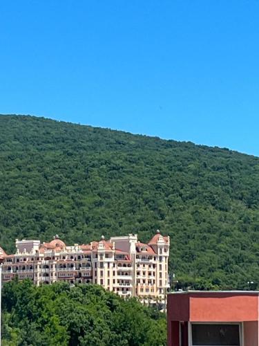 a large building in front of a mountain at Amore Apart Apartments in Burgas City