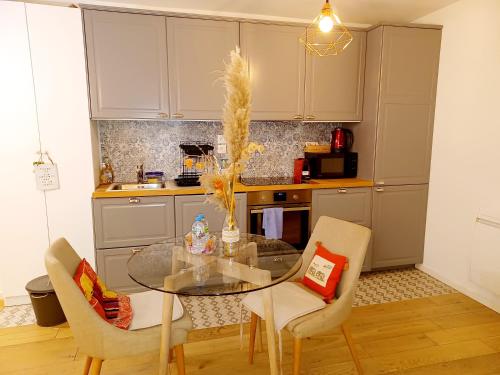 Una cocina con una mesa de cristal y sillas. en 2 beds, modern building, with mobile AC, Paris Expo, 7' metro 2 steps to Paris, en Montrouge