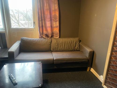 a brown couch in a living room with a window at MOJITO`s ROOM in Lorenskog