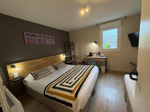 a bedroom with a bed and a desk and a window at Brit Hotel Quimper Nord in Ergué-Gabéric