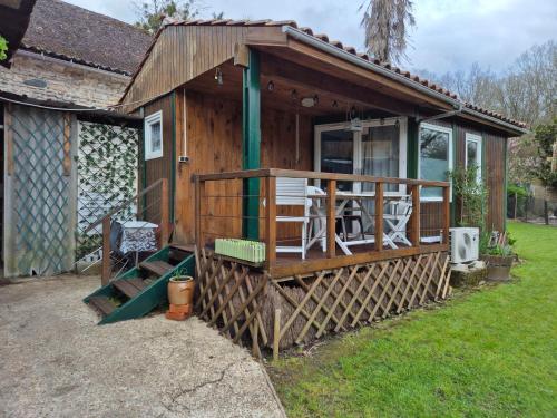 a large wooden cabin with a porch and chairs at Chez Bouju in Castetnau-Camblong