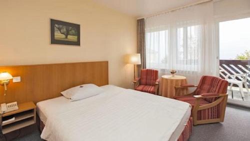 a bedroom with a large white bed and two chairs at Panorama Hotel Oberwiesenthal in Kurort Oberwiesenthal