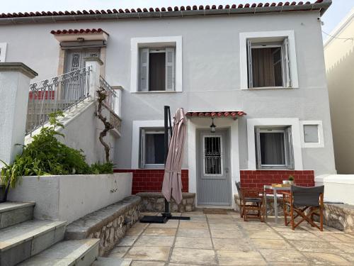 a white house with a table and an umbrella at MantasHouse in Spetses
