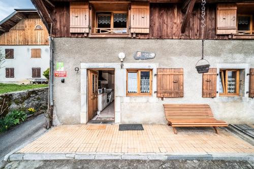 a wooden bench sitting in front of a building at Gite La Ferme de la plaigne in Taninges