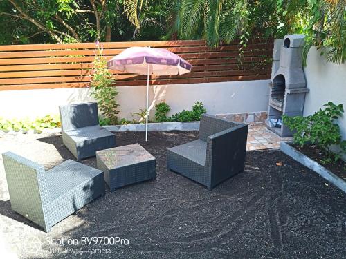 a patio with two chairs and a table and an umbrella at Wakerasuites in Les Abymes