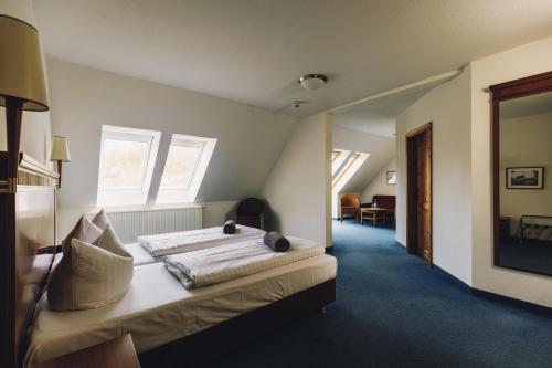 a bedroom with a bed in a room with windows at Seehotel Heidehof in Klein Nemerow