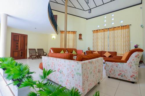 a living room with orange couches and plants at Limeshine - Airport Transit Hotels & Residences in Katunayake