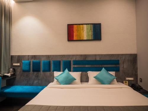 a bedroom with a large bed with blue pillows at Hotel Grand Sudhan in Thanjāvūr
