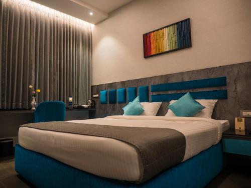 a bedroom with a large bed with a blue headboard at Hotel Grand Sudhan in Thanjāvūr