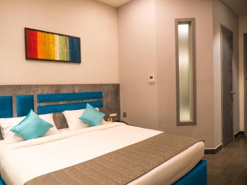 a bedroom with a large white bed with blue pillows at Hotel Grand Sudhan in Thanjāvūr