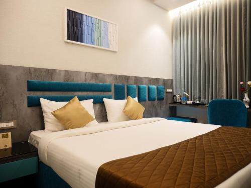 a bedroom with a large bed with a blue headboard at Hotel Grand Sudhan in Thanjāvūr