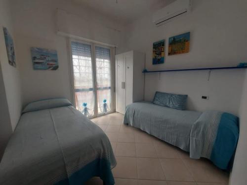 a bedroom with two beds and a window at Appartamenti Le Brocche di Biancospino in LʼAmericano