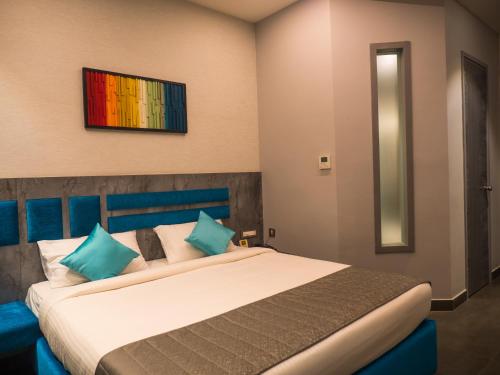 a bedroom with a large bed with blue pillows at Hotel Grand Sudhan in Thanjāvūr