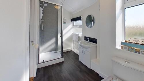 a white bathroom with a shower and a sink at G17 St Meva, Riviere Towans in Hayle