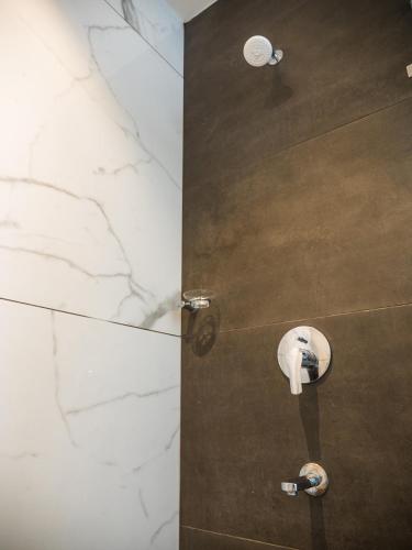 a bathroom with a shower with a stone wall at Hotel Grand Sudhan in Thanjāvūr