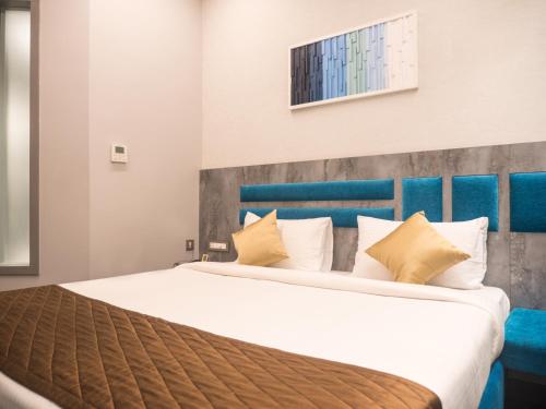 a bedroom with a large white bed with yellow pillows at Hotel Grand Sudhan in Thanjāvūr