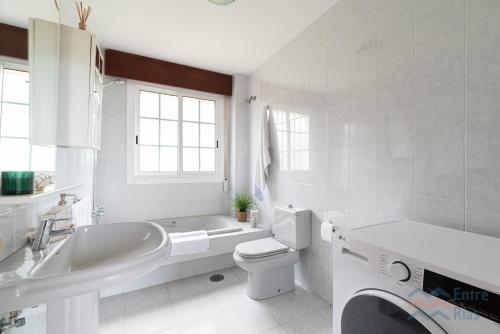 a white bathroom with a tub and a toilet and a sink at Casa de Pili - by entreRías in Cangas de Morrazo