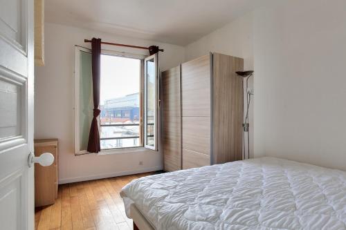 une chambre avec un lit et une grande fenêtre dans l'établissement Cocon calme et lumineux - Clichy, à Clichy