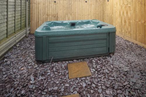 a green bath tub sitting in the corner of a fence at 4 Bedroom, Sleeps 8, 3 Bathroom, Hot Tub, WiFi, Smart TVs in Each Room 3 min walk to KINGSHOLM Stadium in Gloucester