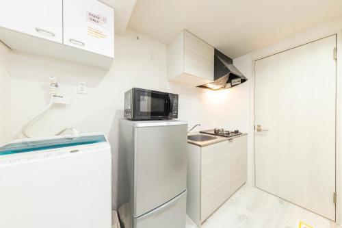 a small kitchen with a refrigerator and a microwave at Tsubaki in Tokyo