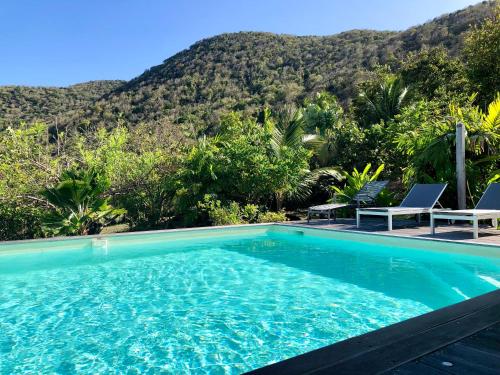 a swimming pool with a mountain in the background at Villa Bambou, vue mer, panorama sur la baie des Saintes in Terre-de-Bas