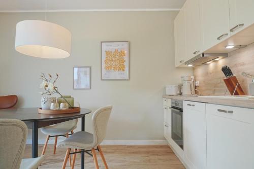 a kitchen with white cabinets and a table and chairs at Charmante TOP Ferienwohnung Wippsteert auf Rügen, großer Garten und Sonnen Terrasse am Golf Platz und Nationalpark Jasmund in Lohme